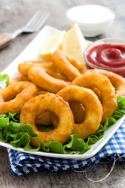 Marul ve ahşap zemin üzerine ketçap ile kızarmış kalamar halkaları