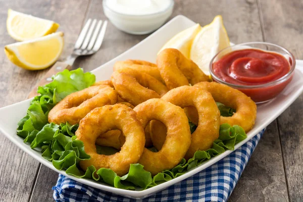 Fried calamari rings with lettuce and ketchup on wooden background — Stock Photo, Image