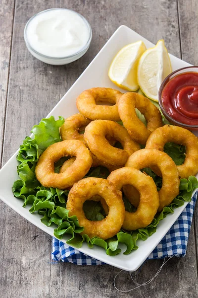 Fried calamari rings with lettuce and ketchup on wooden background — Stock Photo, Image