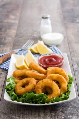 Marul ve ahşap zemin üzerine ketçap ile kızarmış kalamar halkaları