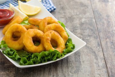 Marul ve ahşap zemin üzerine ketçap ile kızarmış kalamar halkaları