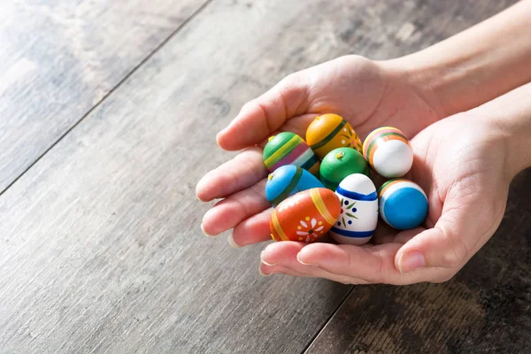 Hands showing Easter eggs, on wooden table. Copyspace. — Stock Photo, Image