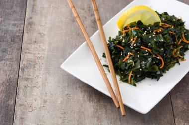WAKAME salata havuç, susam ve platel ahşap masa üzerinde limon suyu ile