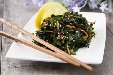 WAKAME salata havuç, susam ve limon suyu plaka üzerinde ahşap masa