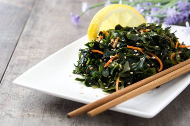 WAKAME salata havuç, susam ve limon suyu plaka üzerinde ahşap masa