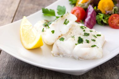 Kızarmış morina fileto ve ahşap arka plan üzerinde plaka salata