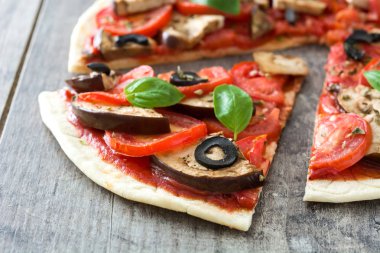 Patlıcan, domates, Siyah Zeytin, kekik ve fesleğen ahşap arka plan üzerinde vejetaryen pizza