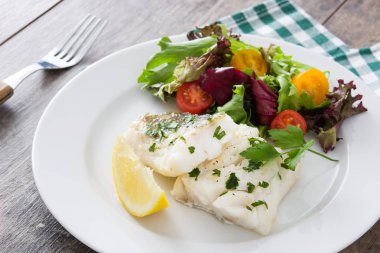 Kızarmış morina fileto ve ahşap arka plan üzerinde plaka salata