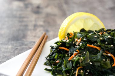 WAKAME salata havuç, susam ve limon suyu plaka üzerinde ahşap masa