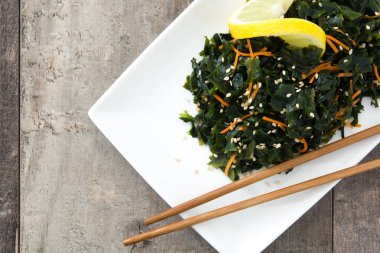 WAKAME salata havuç, susam ve limon suyu plaka üzerinde ahşap masa