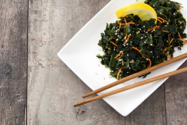 WAKAME salata havuç, susam ve limon suyu plaka üzerinde ahşap masa