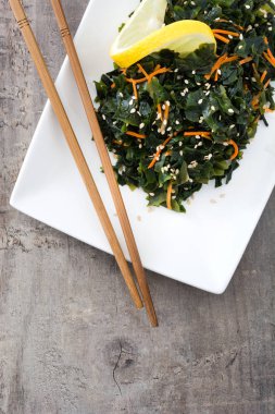 WAKAME salata havuç, susam ve limon suyu plaka üzerinde ahşap masa