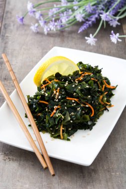 WAKAME salata havuç, susam ve limon suyu plaka üzerinde ahşap masa