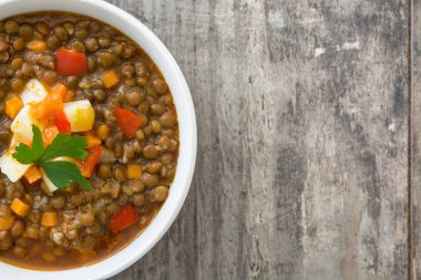 Ahşap arka plan üzerinde bir kasede mercimek çorbası