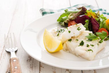 Kızarmış morina fileto ve Beyaz ahşap zemin üzerinde plaka salata