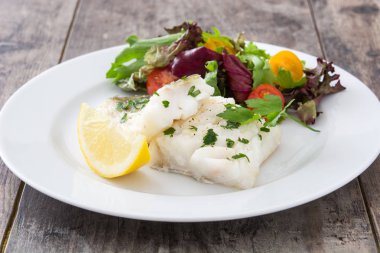 Kızarmış morina fileto ve ahşap arka plan üzerinde plaka salata