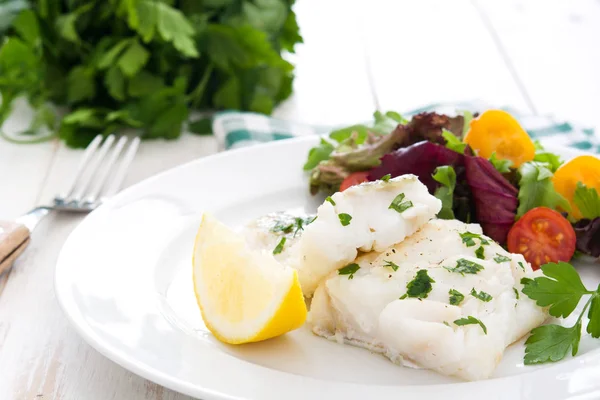 Gebratenes Kabeljaufilet und Salat im Teller auf weißem Holzhintergrund — Stockfoto