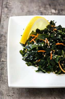 WAKAME salata havuç, susam ve limon suyu plaka üzerinde ahşap masa