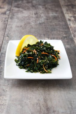 WAKAME salata havuç, susam ve limon suyu plaka üzerinde ahşap masa