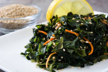 WAKAME salata havuç, susam ve limon suyu plaka üzerinde ahşap masa