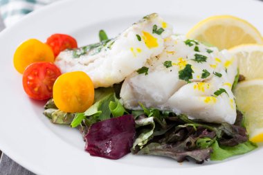 Kızarmış morina fileto ve ahşap arka plan üzerinde plaka salata