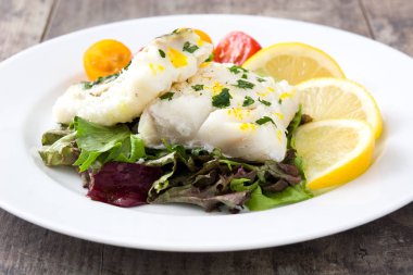 Kızarmış morina fileto ve ahşap arka plan üzerinde plaka salata