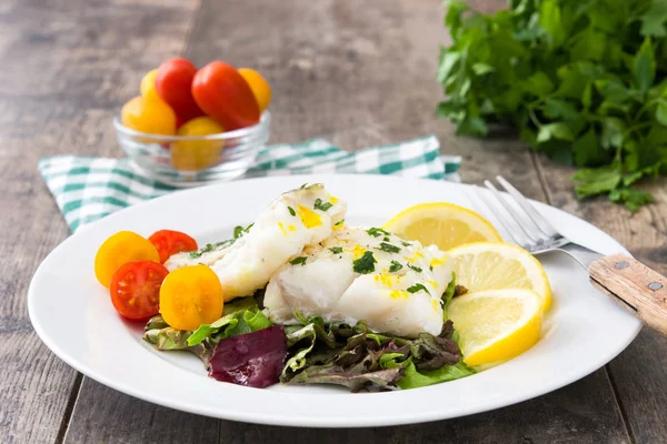 Kızarmış morina fileto ve ahşap arka plan üzerinde plaka salata