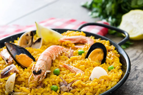 Paella tradizionale spagnola di frutti di mare su sfondo di legno — Foto Stock