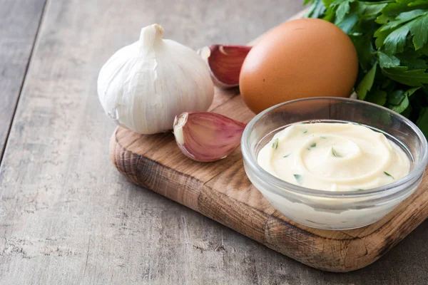 Aioli saus en ingrediënten op houten achtergrond — Stockfoto