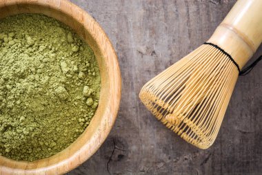 Ahşap arka plan üzerine bir kase ve bambu çırpma teli Matcha yeşil çay