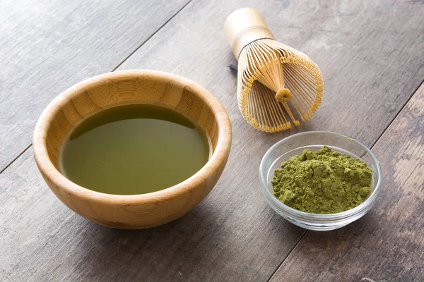 Matcha chá verde em uma tigela e batedor de bambu, em fundo de madeira — Fotografia de Stock