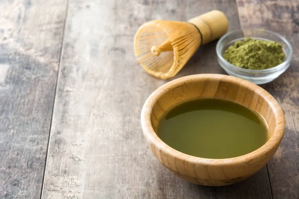 Matcha chá verde em uma tigela e batedor de bambu, em fundo de madeira — Fotografia de Stock
