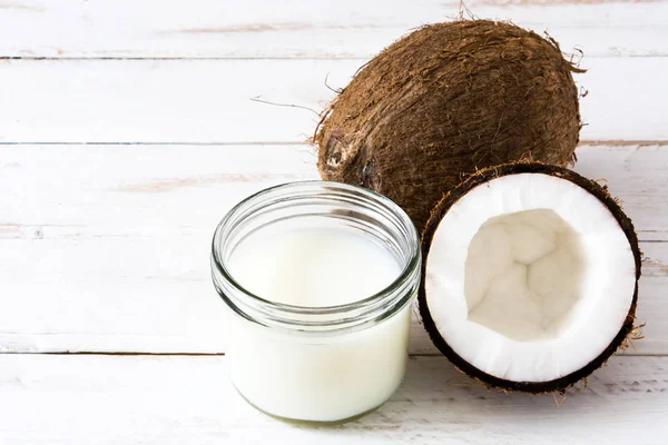 Leche de coco y coco sobre mesa de madera blanca —  Fotos de Stock