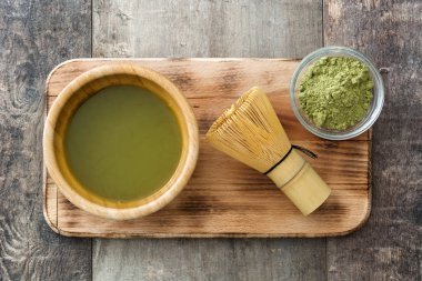 Ahşap arka plan üzerine bir kase ve bambu çırpma teli Matcha yeşil çay