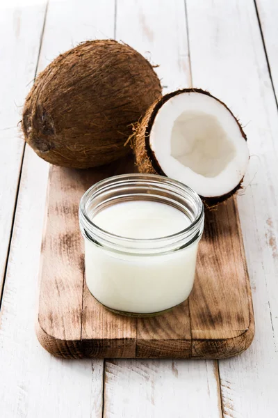 Leite de coco e coco sobre mesa de madeira branca — Fotografia de Stock