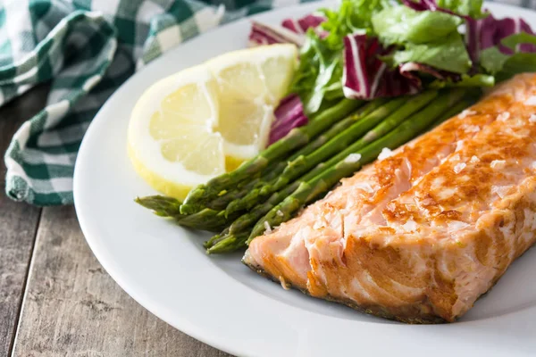 Grilled salmon fillet with asparagus and salad in plate on wooden table — Stock Photo, Image