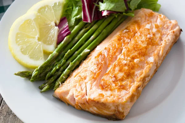 Grilled salmon fillet with asparagus and salad in plate on wooden table — Stock Photo, Image