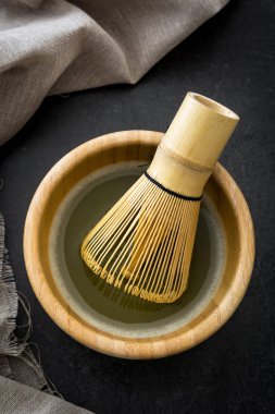 Bir kase ve bambu çırpma teli üzerinde siyah arduvaz Matcha yeşil çay