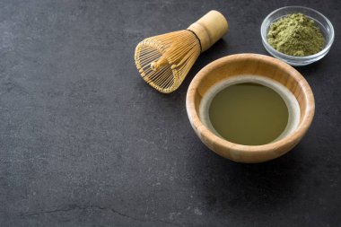Bir kase ve bambu çırpma teli üzerinde siyah arduvaz Matcha yeşil çay