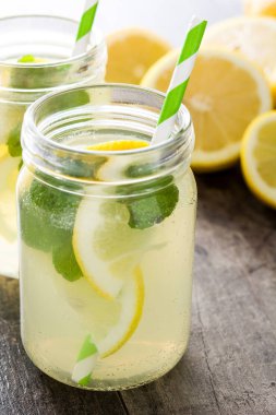 Ahşap arka plan üzerinde bir kavanoz cam limonata içmek. 