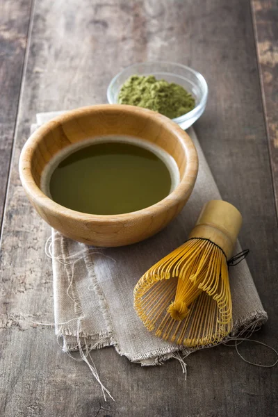 Té verde matcha en un tazón y batidor de bambú en una mesa de madera —  Fotos de Stock