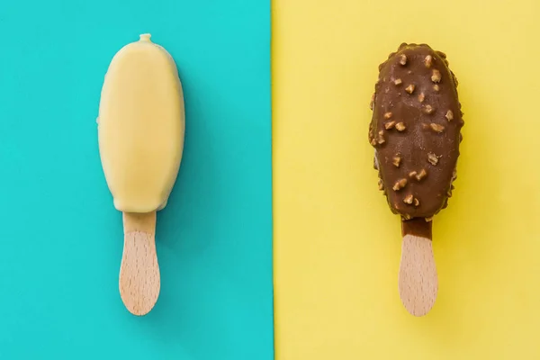 Picolés de sorvete de chocolate preto e branco em fundo amarelo e azul — Fotografia de Stock