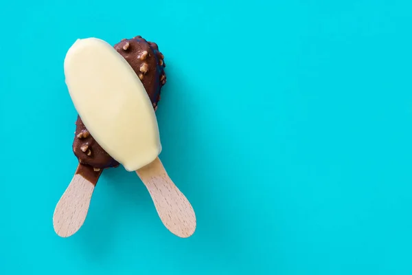 Μαύρο και άσπρο παγωτό σοκολάτα popsicles σε μπλε φόντο. — Φωτογραφία Αρχείου