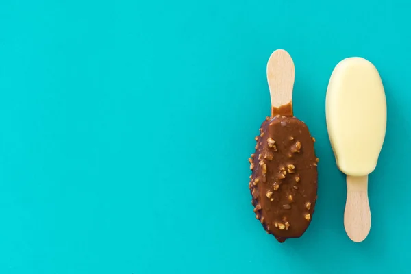 Svart och vit choklad glass popsicles på blå bakgrund. — Stockfoto