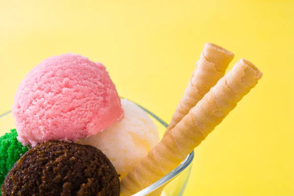 Ice cream scoops in crystal bowl on yellow background — Stock Photo, Image