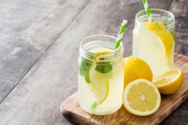 Ahşap arka plan üzerinde bir kavanoz cam limonata içmek.