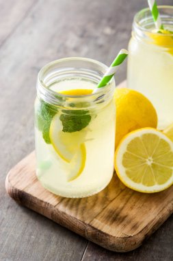 Ahşap arka plan üzerinde bir kavanoz cam limonata içmek.