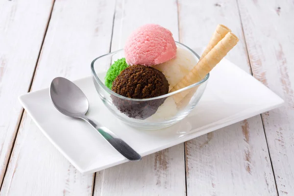 Ice cream scoops in crystal bowl on white wooden background. — Stock Photo, Image