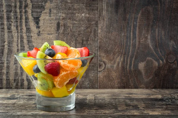 Ensalada de frutas en tazón de cristal sobre madera — Foto de Stock