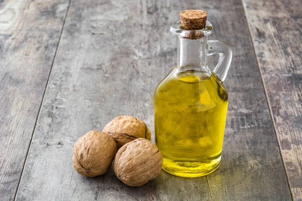 Walnuts oil on wooden background — Stock Photo, Image